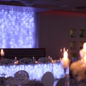 ukrašeni stol za mladence u sali za svadbe Velika dvorana u restoranu Taverna Kraljevec izdaleka slikano s bijelim lampicama